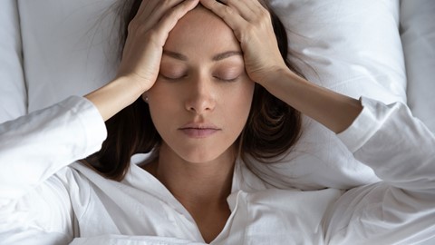 Vrouw met stress, hoofdpijn en veel aan haar hoofd in bed