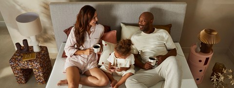 Man en vrouw met kind op bed met kopje koffie